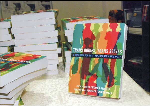 Picture of a table with several copies (including one that's proppsed up) of the Trans Bodies, Trans Selves book